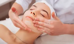 Una donna riceve un trattamento viso con schiuma. Per una pelle luminosa, chiediti ogni quanto fare la pulizia del viso.