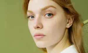 Rostro de mujer joven con pecas y ojos azules. Su cabello es pelirrojo. ¿Glicación qué es? Podría afectar la piel.