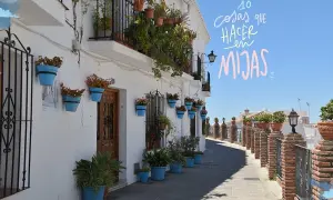Calle empedrada con casas blancas adornadas con macetas azules y flores. Un camino perfecto para descubrir qué ver en Mijas en una tarde.