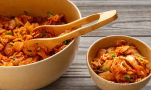 Två skålar med kryddig, fermenterad mat, troligen kimchi, med träklämmor i den större skålen.