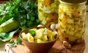 Słoiki z cukinią w zalewie słodko-kwaśnej z curry, miseczka z marynowaną cukinią, świeża cukinia, czosnek i natka pietruszki.