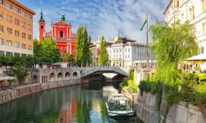 Lublana atrakcje: rzeka Ljubljanica, Most Potrójny, kościół Franciszkanów i łódź wycieczkowa.