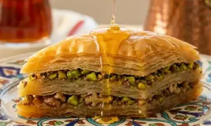 Delizioso baklava ricetta con strati di pasta fillo, pistacchi e noci, inzuppato in sciroppo dorato.