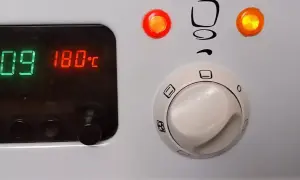 Cyfrowy wyświetlacz piekarnika Mastercook pokazuje 180°C. Pokrętła sterujące i kontrolki są widoczne.