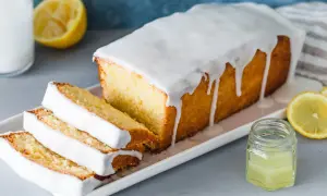 Saftiger Zitronenkuchen mit Zuckerguss, perfekt für ein einfaches zitronenkuchen rezept. Dazu frische Zitronenscheiben und ein kleines Glas Zitronensaft.