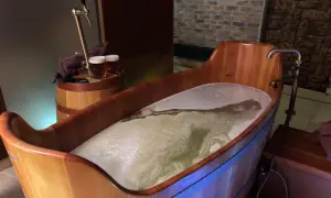 Entspannendes Bier-Wellness-Erlebnis in Tschechien: Ein hölzerner Bottich gefüllt mit schäumendem Bier, daneben ein Zapfhahn und zwei Biergläser.