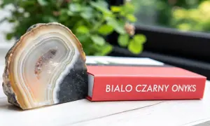 Onyks dla jakiego znaku zodiaku? Piękny, pasiaste agat obok czerwonej książki z napisem "Biało Czarny Onyks".