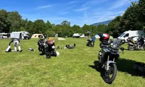 Motocykle zaparkowane na kempingu, w tle namioty i kampery.