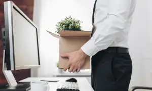 Un employé quitte son bureau, emportant ses affaires dans un carton. Il s'apprête à recevoir son solde tout compte imposable.