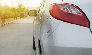 Gros plan sur les feux de position arrière d'une voiture blanche garée sur le bord de la route, avec un éclairage doux.