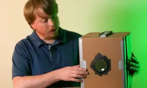 Mężczyzna pokazuje, jak zrobić camera obscura z kartonu. Prosty projekt DIY.