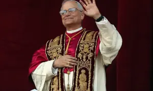 Papież w bogato zdobionej szacie pozdrawia wiernych. Jego uśmiech i gest ręki budzą nadzieję, a jego strój przypomina o tym, skąd pochodzi papież i jego dziedzictwo.