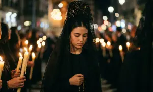 Joven con mantilla negra y rosario, participando en una procesión nocturna. El protocolo para vestir de mantilla se respeta.
