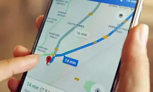 Palec wskazuje na mapę na ekranie telefonu, pokazując trasę i czas dojazdu. Dowiedz się, jak wysłać pinezkę, by udostępnić lokalizację.