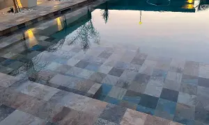 Escalones de baldosas de piedra entran en unas piscinas interiores, reflejando luces y árboles.