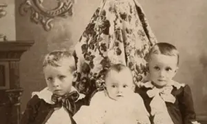 Trójka dzieci, w tym niemowlę, pozuje do portretu. Czy Isamu ma dzieci? Ta fotografia sugeruje, że tak, ma co najmniej trójkę.
