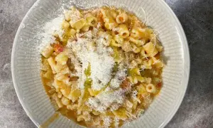 En skål med pasta och potatis, toppad med riven ost och en skvätt olivolja. En härlig och mättande rätt.