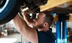 Mechanik sprawdza podwozie auta. Dowiedz się, ile kosztuje przegląd samochodu z gazem.