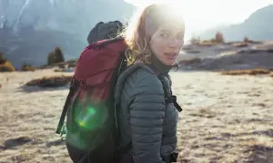 Kobieta z plecakiem w górach, gotowa na przygodę. To prawdziwy backpacking po polsku, z widokiem na majestatyczne szczyty.