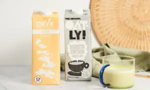 Dwa kartony mleka roślinnego (DRYK i Oatly) oraz szklanka zielonego napoju.