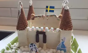 En fantasifull glasstårta formad som ett slott, perfekt för barn. Med svenska flaggan på toppen och dekorerad med marshmallows, strössel och söta figurer.
