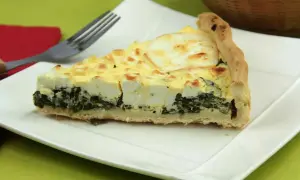 Rebanada de quiche de espinacas con queso feta y una corteza dorada, lista para ser disfrutada.