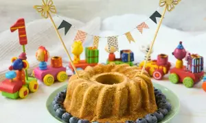 Saftiger Kuchen ohne Zucker für Kinder, dekoriert mit Blaubeeren und bunten Holzspielzeugen. Perfekt für den ersten Geburtstag!