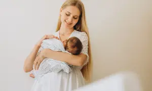 Szczęśliwa mama z niemowlęciem na rękach. To piękny okres karmienia piersią, pełen bliskości i miłości.