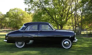 Svart Vauxhall Cresta parkerad på en gräsmatta med träd i bakgrunden.