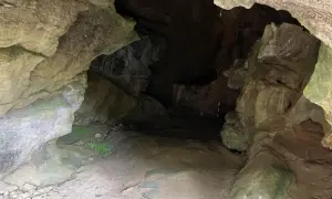 Entrada a la cueva de la Loja, con rocas irregulares y un camino de tierra que se adentra en la oscuridad.