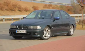 Ciemnozielone BMW E39 z polskimi tablicami WF 65015 stoi na parkingu.