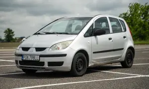 Srebrny Mitsubishi Colt z tablicą rejestracyjną PGN 798LL stoi na parkingu.
