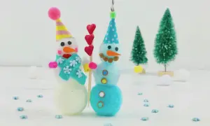 Zwei süße Schneemänner, perfekt zum Basteln Weihnachten Kinder. Sie tragen bunte Mützen und Schals, umgeben von kleinen Weihnachtsbäumen.