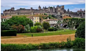 Majestatyczna twierdza Carcassonne góruje nad miastem, otoczona zielenią i rzeką.