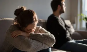 Kobieta skulona, smutna, czuje się nie ważna dla partnera, który odwrócił się do niej plecami.