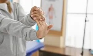 Person stretchar handleden för musarm behandling.