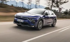 Granatowy Citroën C5 X, nowoczesny mpv, pędzi po krętej drodze wśród wzgórz.