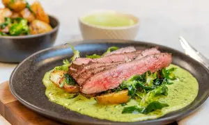 Skivad flankstek med perfekt innertemp, serverad med rostade potatisar och en krämig örtsås.