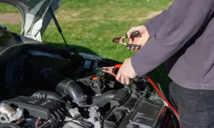 Persona conectando pinzas al coche para arrancar la batería.