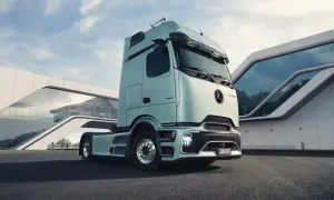 Le dernier camion Mercedes, d'un bleu pâle, est garé devant un bâtiment moderne aux formes courbes et vitrées.