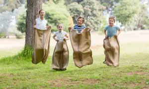 Niños compiten en una divertida carrera de sacos en un día soleado en el parque.