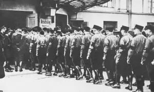 Männer in Uniformen marschieren vor dem Reichstag. Die Szene erinnert an die Zeit der deutschen Zentrumspartei, als politische Organisationen eine wichtige Rolle spielten.