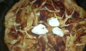 Ein frisch gebackener Apfel-Scheiterhaufen mit Zimt und drei Klecksen Sahne. Ein köstliches Rezept für gemütliche Stunden.
