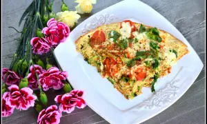 Pyszny omlet z tuńczykiem, pomidorami i zielonymi warzywami, udekorowany kwiatami.