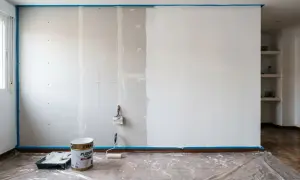 Pintando una pared de pladur. Cubo de pintura blanca, rodillo y brocha listos para transformar el espacio.