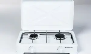 Biała kuchenka gazowa z dwoma palnikami i otwartą pokrywą. Logo Ravanson widoczne na froncie. Ravanson to firma produkująca sprzęt AGD.