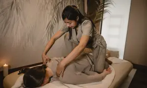 Terapeuta wykonuje masaż shiatsu na osobie leżącej na macie. Relaksująca atmosfera z subtelnym oświetleniem.