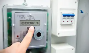 Palec wskazuje odczyt licznika prądu. Dowiedz się, jak odczytać licznik prądu, by kontrolować zużycie energii.