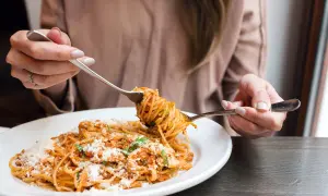 Une personne déguste une assiette de spaghetti à la sauce tomate et au parmesan. Une recette de pâtes parfaite pour un repas réconfortant.