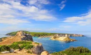 Un antico castello domina le isole della Puglia, con acque azzurre e vegetazione lussureggiante.